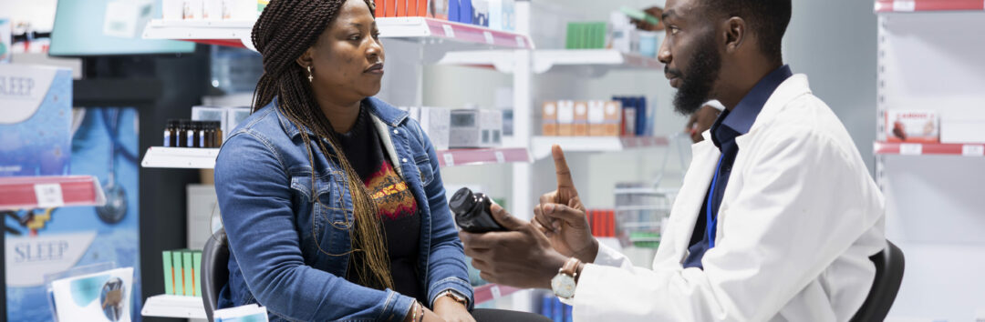 Professional black pharmacist providing expert medication advice to a female customer at the drugstore, explaining dosage and treatment options during a routine consultation service.
